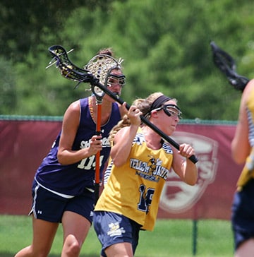IWLCA Presidents Cup A lacrosse player attempts to score while an opponent defends her