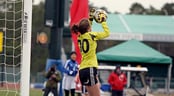 Disney Soccer Showcase (Girls) A female goal keeper stops a shot on goal during a soccer match