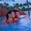 A couple relaxes in a pool at sunset