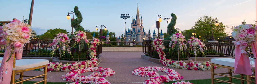 East Plaza Garden Florida Weddings Wishes Collection Disney S Cinderella S Castle Stands In The Background Of An Outdoor Wedding Venue Set With Chairs And Fl