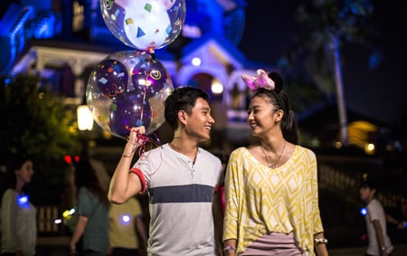 A man and a woman share smiles in front of Mystic Manor after nightfall