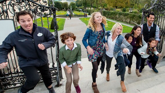 Travelers walking up a flight of steps with an Adventures by Disney Guide