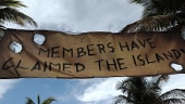 A banner strung with rope by palm trees that reads MEMBERS HAVE CLAIMED THE ISLAND