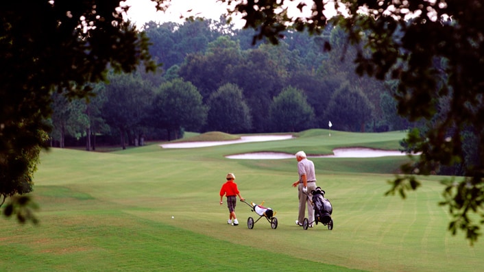 A grandfather and grandson walking on a golf course