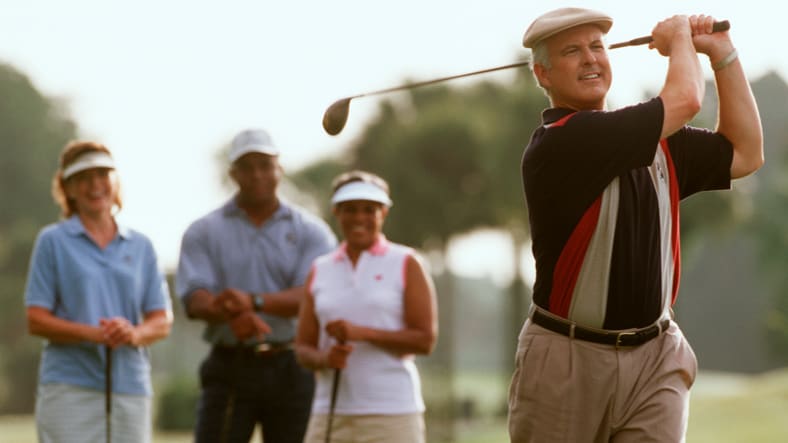 A man driving a golf ball as his friends watch