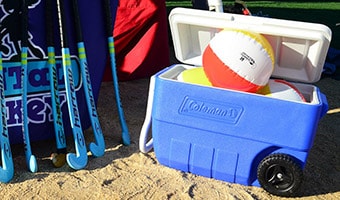 Cooler Policy Six field hockey sticks standing next to a cooler holding 3 beach balls