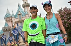 Mike Wazowski and Sulley runners in front of Sleeping Beauty Castle during Disneyland Half Marathon Weekend.