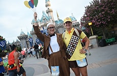 Runners dressed as characters from "Up" pose in front of Sleeping Beauty Castle at Disneyland Park during Disneyland Half Marathon Weekend.