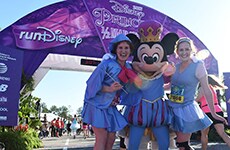 Runners pose with Mickey Mouse at the finish line of Disney Princess Half Marathon at Walt Disney World Resort.