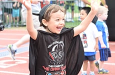 Kid runner celebrates after running the runDisney Kids Races during Star Wars Half Marathon – The Dark Side race weekend