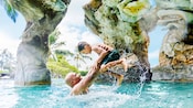 A father and son enjoy the waterfall pool at Aulani resort A father and son enjoy the waterfall pool at Aulani resort