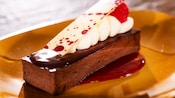 A chocolate torte topped with cream, a raspberry and white chocolate