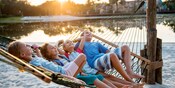 Quatro crianças relaxam em uma rede perto de uma lagoa Quatro crianças relaxam em uma rede perto de uma lagoa