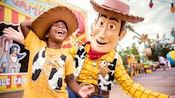 Un jeune garçon portant un t-shirt sur le thème de Woody et un chapeau de cowboy rit alors qu’il interagit avec Woody à l’intérieur de Toy Story Land Un jeune garçon portant un t-shirt sur le thème de Woody et un chapeau de cowboy rit alors qu’il interagit avec Woody à l’intérieur de Toy Story Land