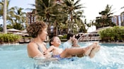 A family of 4 are all smiles while enjoying time in the Waikolohe pool at Aulani Resort A family of 4 are all smiles while enjoying time in the Waikolohe pool at Aulani Resort