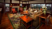 An open living room with a sofa, 2 easy chairs, 2 leather chairs and a wall of windows