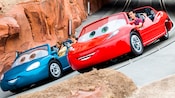 Two vehicles with Guests race around the Radiator Springs track Two vehicles with Guests race around the Radiator Springs track