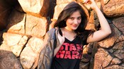 A woman holds a jacket while wearing a shirt with words that read Star Wars