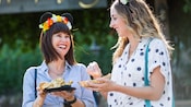 Two women laugh as they enjoy food from the Festival Marketplace