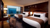 Two queen beds sharing a Sleeping Beauty Castle headboard, a desk, TV-dresser and an easy chair