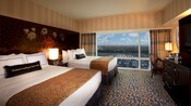 Two queen beds sharing a Sleeping Beauty Castle headboard, a TV-dresser and a desk