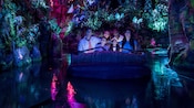 Guests gaze in wonder while floating through a bioluminescent rainforest aboard Na’vi River Journey