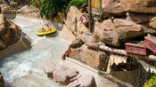 Una madre con sus 2 hijos ríen mientras se mojan en el descenso en balsa por Gangplank Falls