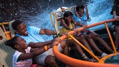 A laughing family of four get splashed while enjoying Kali River Rapids