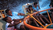 A laughing family of four get splashed while enjoying Kali River Rapids