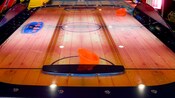 Air hockey table with a wooden table top and 2 strikers