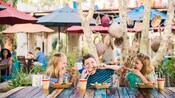 Three kids enjoy kabobs and beverages at an outdoor table Three kids enjoy kabobs and beverages at an outdoor table