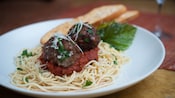 Plate with 2 large meatballs atop marinara sauce and spaghetti