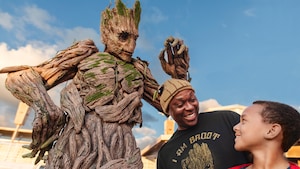 A man and a boy stand next to Groot