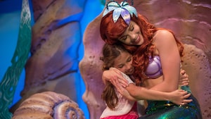 Ariel, the Little Mermaid, hugging a young girl
