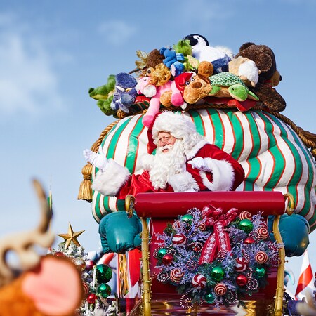 Santa Claus waves from his sleigh with a bag full of plush toys