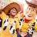 Um menino usando uma camiseta temática do Woody e chapéu de caubói rindo e interagindo com o Woody dentro da Toy Story Land