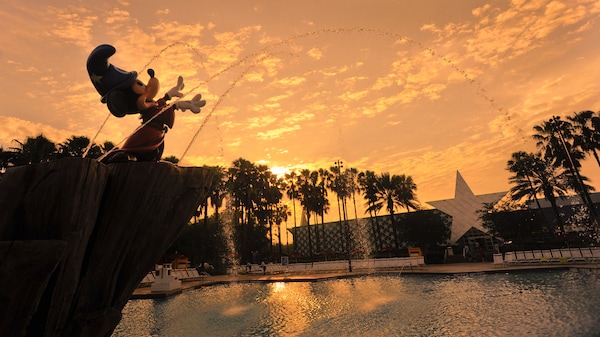 Silhouette against a sunset sky of Sorcerer Mickey Fountain at Fantasia Pool at Disney’s All-Star Movies Resort