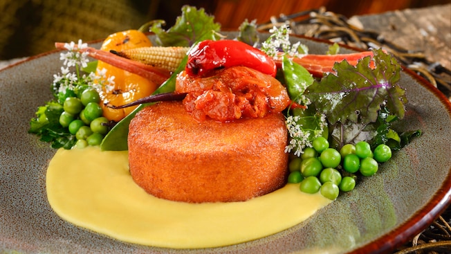 A maze cake paired with peas, lettuce, corn, carrots, peppers, cream and tomato sauce
