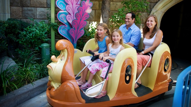 A family of 4 rides inside a giant caterpillar through the Alice in Wonderland attraction