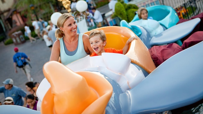 A mother and her little boy smile as they ride Dumbo the Flying Elephant