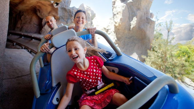 A girl and her parents ride the 3-person Matterhorn Bobsleds vehicles