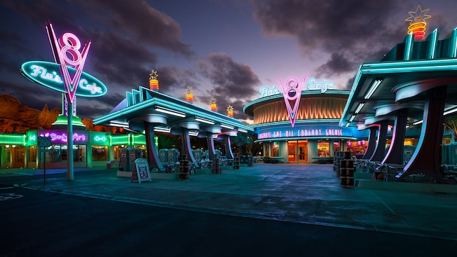 Gas station-themed entrance to Flo's V8 Cafe lit with neon signs at night