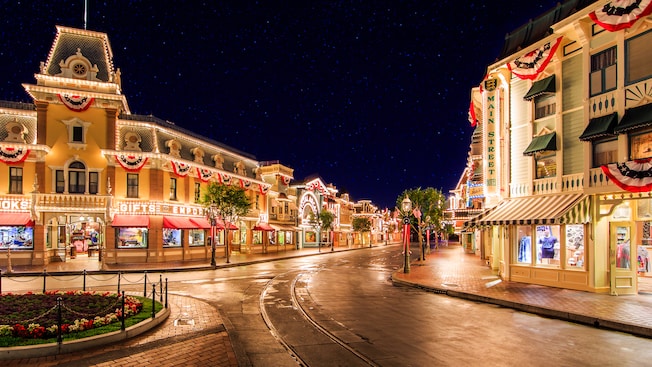 Stars scatter across the night sky as lights illuminate shops and attractions on Main Street, U.S.A.