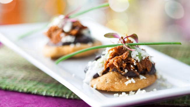 Corn cakes topped with black refried beans, pork, queso fresco, sour cream and tomatillo sauce