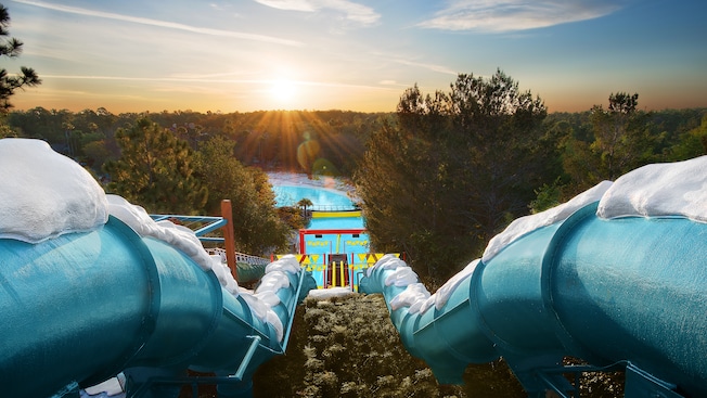 Typhoon Lagoon Vs Blizzard Beach - Which Disney Water Park Is Better? 4 Downhill Double Dipper, side-by-side enclosed waterslides, with the sun rising on the horizon