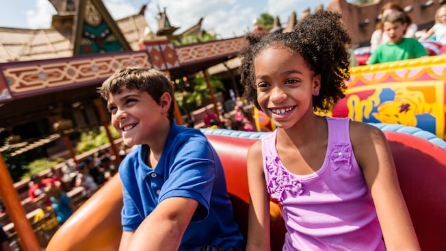A boy and girl ride The Magic Carpets of Aladdin attraction at Magic Kingdom park