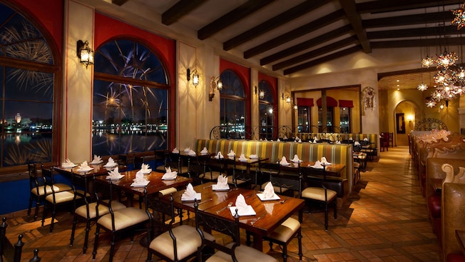 La Hacienda de San Angel dining room with large windows and beamed ceiling, lit up at night