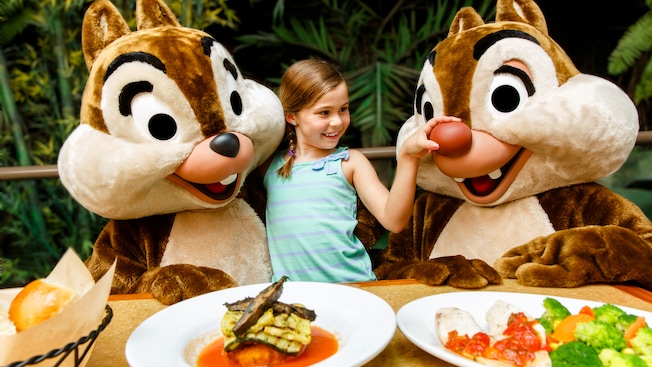 A girl stands between Chip 'n' Dale and squeezes Dale's big red nose at The Garden Grill restaurant