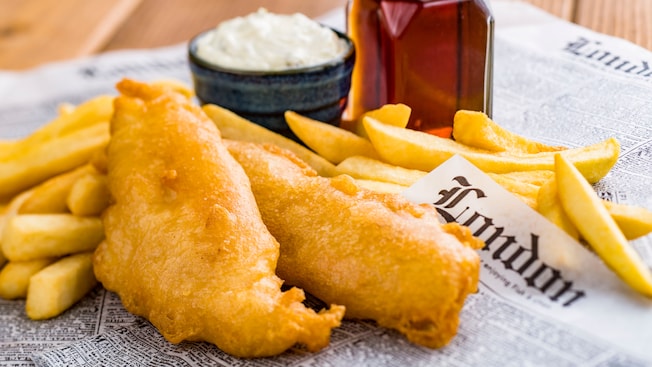 A serving of fish and chips served with malt vinegar and a ramekin of tartar sauce