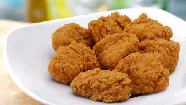 A rounded dish contains 8 breaded and fried chicken nuggets